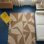 High angle view of the Sand Fragments rug on a blue floor, showcasing how the neutral geometric design anchors a contemporary living space.