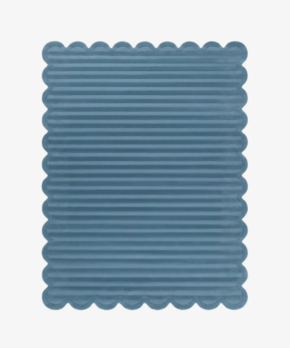 Top down view of a rug from the ScallopedRugs Blue Rugs collection featuring a slate blue color with a carved horizontal ribbed texture and signature scalloped edges.