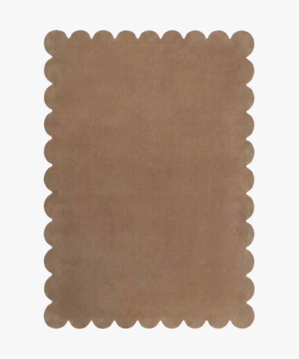 Product shot for the ScallopedRugs Brown Rugs category displaying a solid warm tan colored rug made from hand tufted wool with signature scalloped edges.