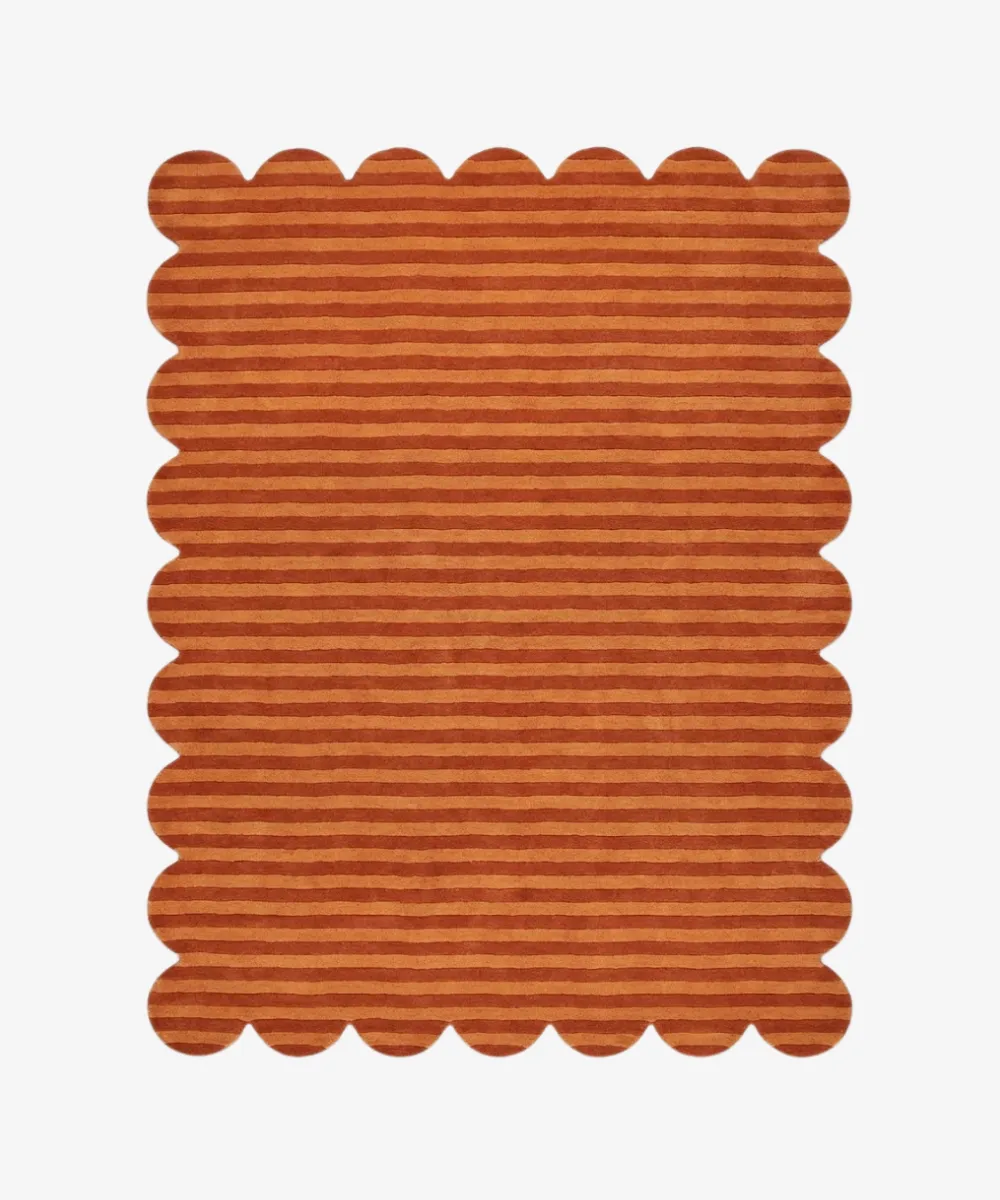 Top down view of a rug from the ScallopedRugs Orange Rugs collection featuring a warm terracotta orange color palette with a horizontal striped pattern and signature scalloped edges.