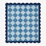 Top down view of the Slate Haven rug featuring a classic diamond checkerboard pattern in soft slate blue and light blue tones, framed by a deep blue scalloped border.