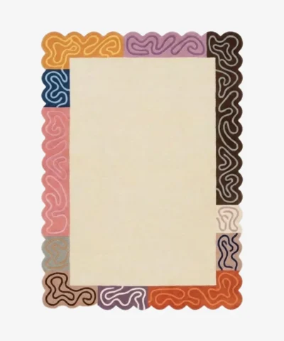 Top down view of the Soft Frame rug featuring a large neutral cream wool center framed by a playful multicolored border of striped blocks in pink, orange, brown, and purple, finished with custom scalloped edges.