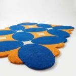 Low angle perspective of the Solar Indigo area rug highlighting the dense plush wool texture and the retro style blue and orange design.