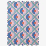 Top down view of the Sugar Trellis rug featuring a retro diamond grid pattern with pink and blue floral motifs and scalloped edges on a hand tufted wool background.