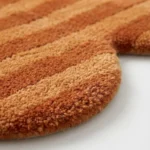 Extreme close up of the Sun Baked rug highlighting the dense plush wool pile and the precise carving of the warm orange stripe pattern.