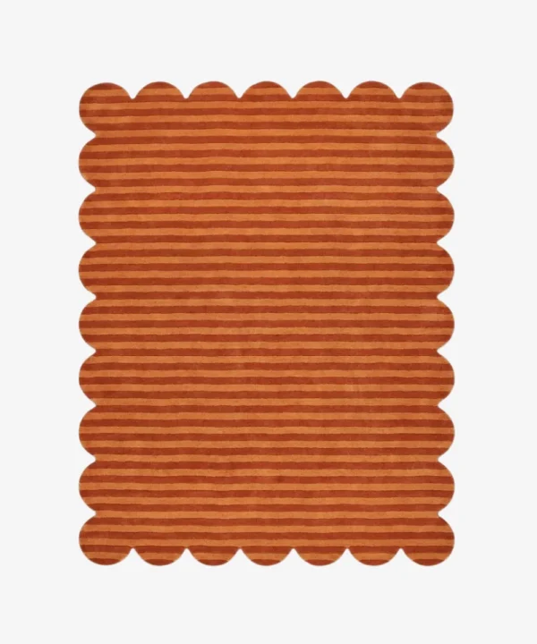 Top down view of the Sun Baked rug featuring warm rust and orange horizontal stripes with a carved texture and scalloped borders.