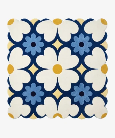 Top down view of the Sun Dot Posy square rug featuring a retro geometric floral pattern with cream and blue flowers on a navy background with scalloped edges.