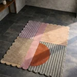 Perspective view of the Terra Rift rug placed on a dark tiled floor, showcasing the plush hand-tufted wool texture and the modern abstract linear pattern.