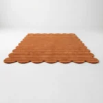 Low angle perspective of the Sun Baked hand tufted rug, showcasing the earthy terracotta tones and the ribbed carved pile design.