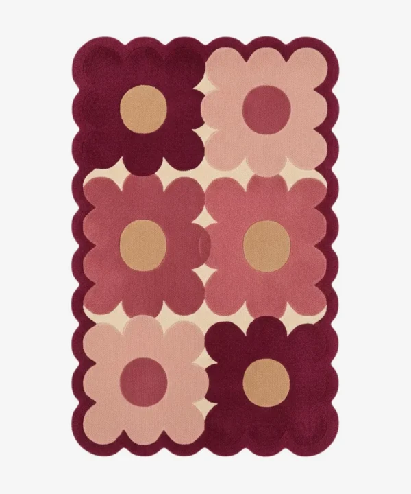 Top down view of the Velvet Garden rug featuring a playful grid pattern of large maroon and dusty pink flowers on a cream wool background, finished with custom scalloped edges.