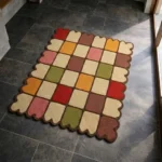 Perspective view of the Autumn Tile Square rug placed on a dark tiled floor, highlighting the retro multi-colored grid design and warm harvest color palette.