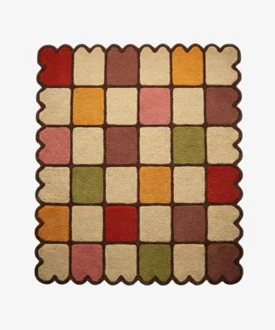 Top down view of the Autumn Tile Square rug featuring a vibrant checkered pattern in earthy red, mustard yellow, olive green, pink, and cream, finished with a dark brown grid and scalloped edge.