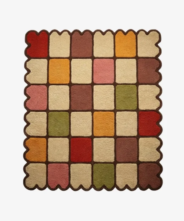 Top down view of the Autumn Tile Square rug featuring a vibrant checkered pattern in earthy red, mustard yellow, olive green, pink, and cream, finished with a dark brown grid and scalloped edge.