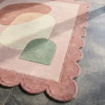 Close-up perspective of the Blush Aurea rug, highlighting the thick hand-tufted wool texture and the precise carving of the pastel geometric shapes.