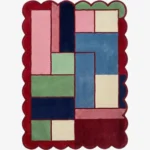 Top down view of the Canvas Mosaic rug featuring a vibrant, multi-colored geometric block design surrounded by a decorative red scalloped border.
