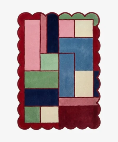 Top down view of the Canvas Mosaic rug featuring a vibrant, multi-colored geometric block design surrounded by a decorative red scalloped border.