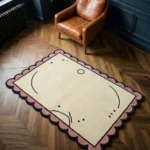 High angle view of the Canvas Scribble rug featuring a cream wool background with abstract black line art, framed by a playful pink and black scalloped border.
