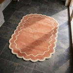 High angle perspective of the Cedar Patio rug placed on a dark tiled floor, highlighting the rich cedar color and soft hand-tufted wool texture.