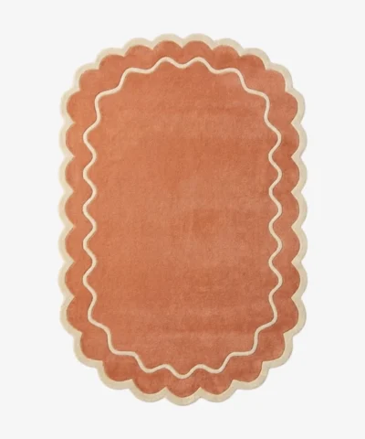Top down view of the Cedar Patio rug featuring a warm rust terracotta background with a decorative cream wavy contour line and scalloped edges.