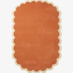 Top down view of the Clay Veranda rug featuring a rich, solid rust terracotta color center framed by a contrasting cream scalloped border.