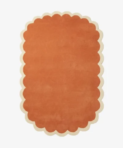 Top down view of the Clay Veranda rug featuring a rich, solid rust terracotta color center framed by a contrasting cream scalloped border.