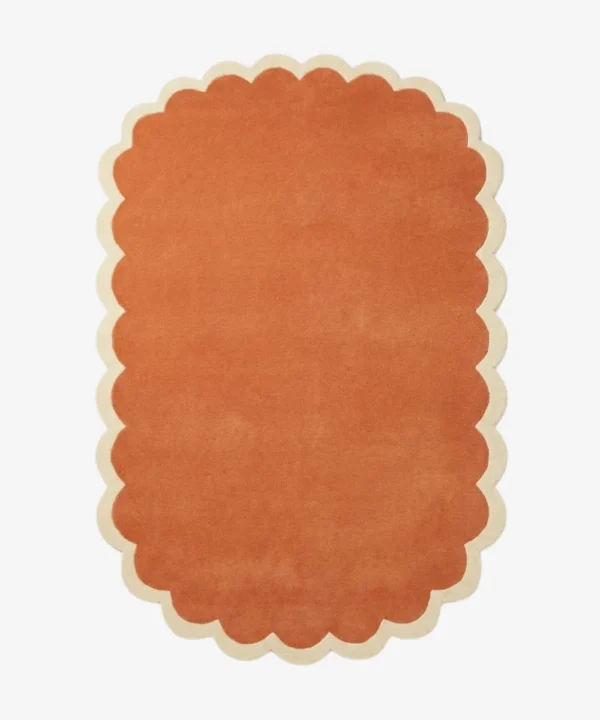 Top down view of the Clay Veranda rug featuring a rich, solid rust terracotta color center framed by a contrasting cream scalloped border.