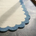 Close-up detail of the Cloud Marina rug's corner, showcasing the plush hand-tufted wool pile and the smooth transition between the cream center and blue edge.