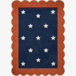 Top down view of the Cosmic Constellation rug featuring a deep navy blue rectangular center with a white star pattern, completely surrounded by a decorative rust orange scalloped border.
