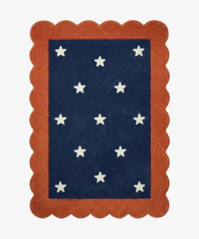 Top down view of the Cosmic Constellation rug featuring a deep navy blue rectangular center with a white star pattern, completely surrounded by a decorative rust orange scalloped border.