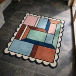 Perspective view of the Dusty Dune rug placed on a dark tiled floor, highlighting the modern abstract block pattern and plush hand-tufted wool texture.