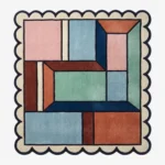 Top down view of the Dusty Dune Square rug featuring a geometric color block design in dusty blue, terracotta, and mint green, framed by a dark blue scalloped border.