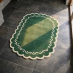 Perspective view of the Emerald Veranda rug placed on a dark tiled floor, highlighting the rich green tones and the vintage-inspired scalloped edge design.