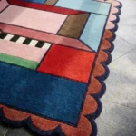 Close-up perspective of the Enclosed Frame rug, highlighting the plush hand-tufted wool texture and the vibrant contrast between the deep blue and rust-colored geometric sections.