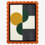 Top-down view of the Everne Meadow hand-tufted wool rug featuring a vibrant orange scalloped border and a modern geometric block pattern with mustard yellow, deep green, and dark grey shapes on a cream background.