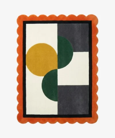 Top-down view of the Everne Meadow hand-tufted wool rug featuring a vibrant orange scalloped border and a modern geometric block pattern with mustard yellow, deep green, and dark grey shapes on a cream background.