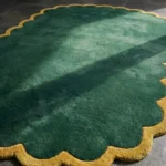 Close-up detail of the Forest Royale rug's corner, showcasing the plush emerald wool pile and the contrasting mustard gold scalloped border.