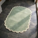 Perspective view of the Garden Lace rug placed on a dark tiled floor, highlighting the calming green tones and the intricate floral border design.