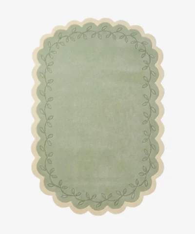 Top down view of the Garden Lace rug featuring a soft sage green center framed by a cream scalloped border with a delicate leafy vine pattern.