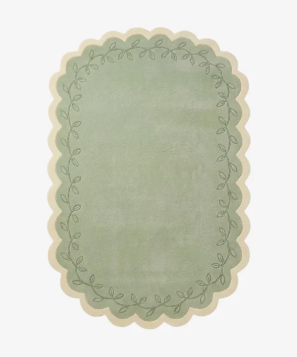 Top down view of the Garden Lace rug featuring a soft sage green center framed by a cream scalloped border with a delicate leafy vine pattern.