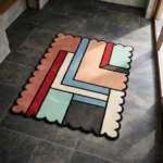 High angle view of the Linear Pathways rug featuring a modern abstract design with interlocking geometric paths in rust, red, blue, and mint, defined by black lines and a scalloped edge.