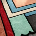 Close-up detail of the Linear Pathways rug, highlighting the plush hand-tufted wool texture and the vibrant color-block pattern with bold black outlines.