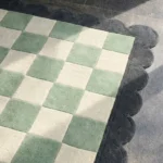 Close-up perspective of the Lune Mist rug, showcasing the plush hand-tufted wool texture and the classic sage and cream check design with a scalloped edge.