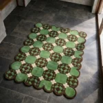Perspective view of the Meadow Tiling rug placed on a dark tiled floor, showcasing the structured geometric tile design and the contoured scalloped border illuminated by natural sunlight.