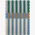 Top-down view of the Mint Gelato rug against a white background, featuring a vibrant color-block striped pattern with vertical bands of purple and dark green on the top half, a transitional band of brown and blue blocks in the center, and alternating cream and light blue stripes on the bottom half, all framed by a continuous scalloped border.