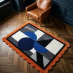 Top down view of the Noctra Apex rug featuring a bold geometric composition with deep blue semi-circles, grey triangles, and black and white accents, finished with a vibrant orange scalloped border.