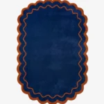 Top down view of the Ocean Garnet rug featuring a solid deep navy blue center framed by a rust orange wavy scalloped border.