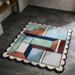 Perspective view of the Pastel Pocket rug placed on a dark tiled floor, highlighting the soft pastel geometric shapes and plush hand-tufted wool texture.