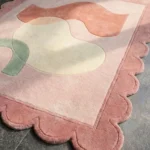 Close-up perspective of the Peach Wisp rug highlighting the plush hand-tufted wool texture and the precise carving of the curved sage and peach shapes.