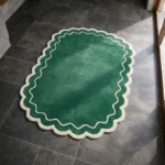 Perspective view of the Pine Estate rug placed on a dark tiled floor, highlighting the rich forest green color and the playful cream wavy edge.