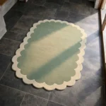 Perspective view of the Pistachio Whale rug placed on a dark tiled floor, highlighting the soft gradient color shift and the plush hand-tufted wool texture.